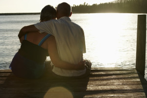 Rear view of happy senior couple sitting on edge of pier by lake