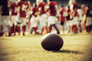 Close up of an american football on the field, players in the ba