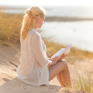 Woman enjoys reading on beautiful sandy beach.
