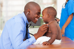 happy african male doctor examining baby boy with female nurse o