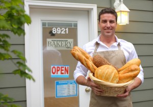 Bakery owner in front of shop with bread