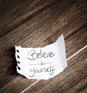 Believe in yourself written on the paper on a wood background